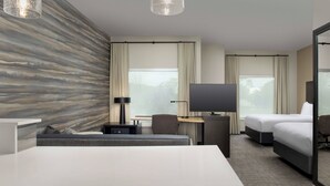 Una habitación de hotel moderna con una cama grande, un escritorio, una silla, un televisor y un sofá.