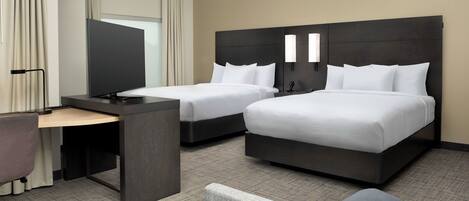 Une chambre d’hôtel avec deux lits, un bureau et une chaise.