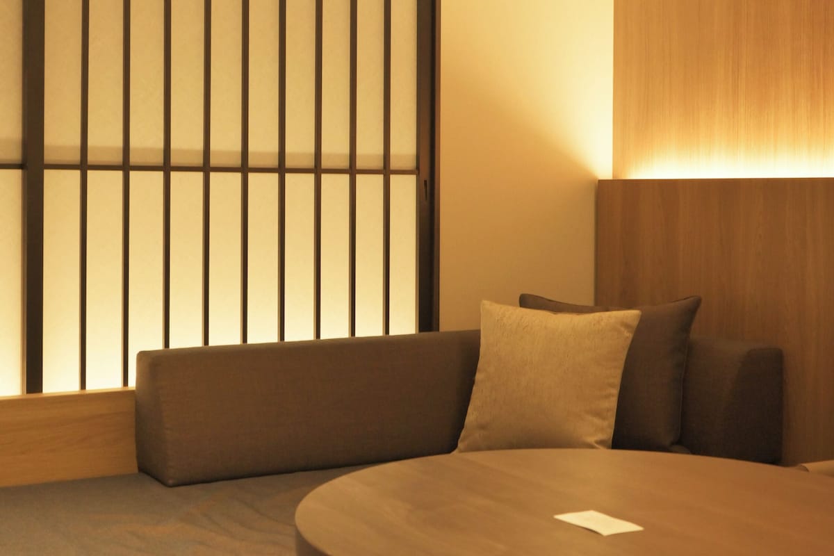 A modern room with a round table, a cushioned bench, and a wooden partition with vertical slats.