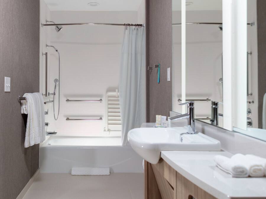 A modern bathroom with a bathtub, shower, and sink.