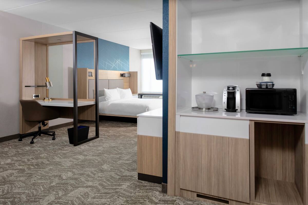 Une chambre d’hôtel équipée d’un lit, d’un bureau, d’une chaise et d’un téléviseur fixé au mur.