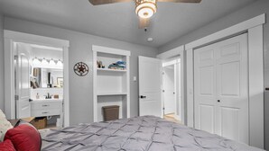 Ein Schlafzimmer mit Bett, Kleiderschrank, Spiegel und Deckenventilator.