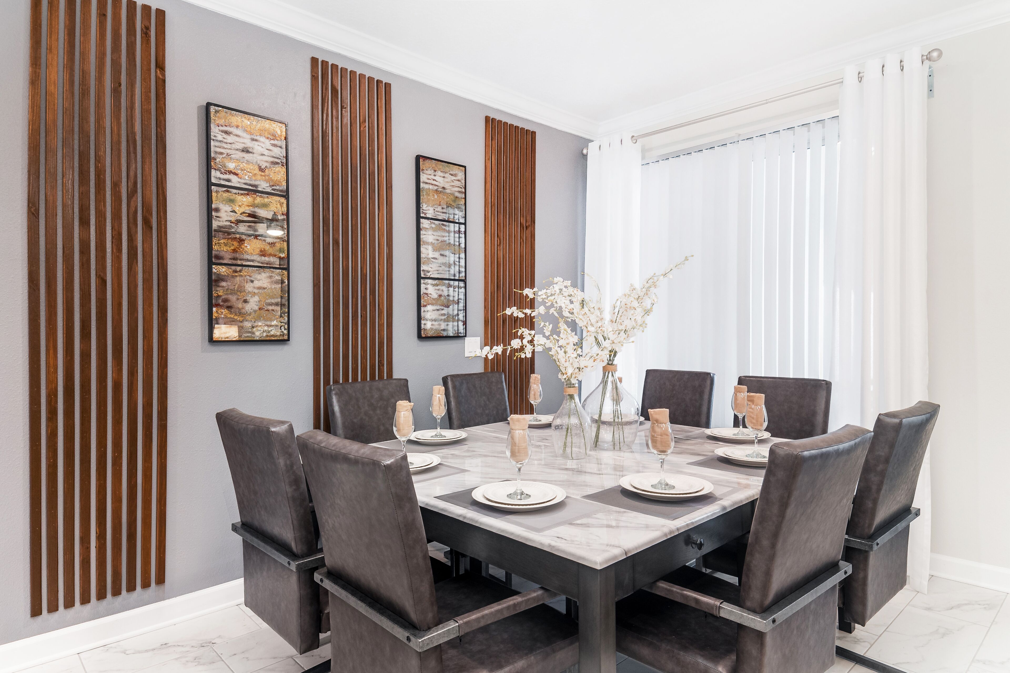Un comedor con una mesa rectangular, seis sillas y un florero con flores.