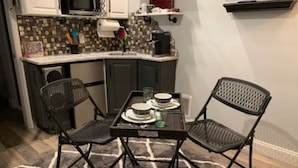Cocina compacta con comedor, que incluye una mesa pequeña con sillas, un microondas y un salpicadero de azulejos.