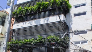 En bygning med flere etager med altaner pyntet med grønne planter, en tydelig indgang og et skilt med teksten '105 Villago Residences'.