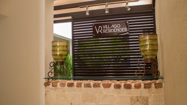 En murstenspejs med et skilt for Villago Residences over sig.