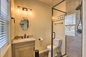 A bathroom with a glass shower enclosure, a sink with a mirror, and a toilet. - Modern Retreat: 3 Blocks to Dtwn Williams + Rte 66 (Williams)