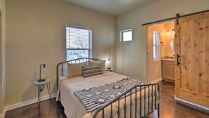 A bedroom with a bed, bedside table, lamp, and a view of the outside. - Modern Retreat: 3 Blocks to Dtwn Williams + Rte 66 (Williams)
