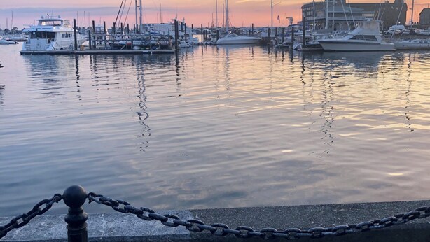 A marina with boats docked at the pier during sunset.
