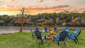 Un espacio de descanso junto al lago con sillas Adirondack y un hogar para la fogata.