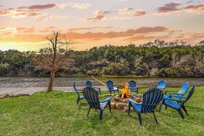 Un espacio de descanso junto al lago con sillas Adirondack y un hogar para la fogata.