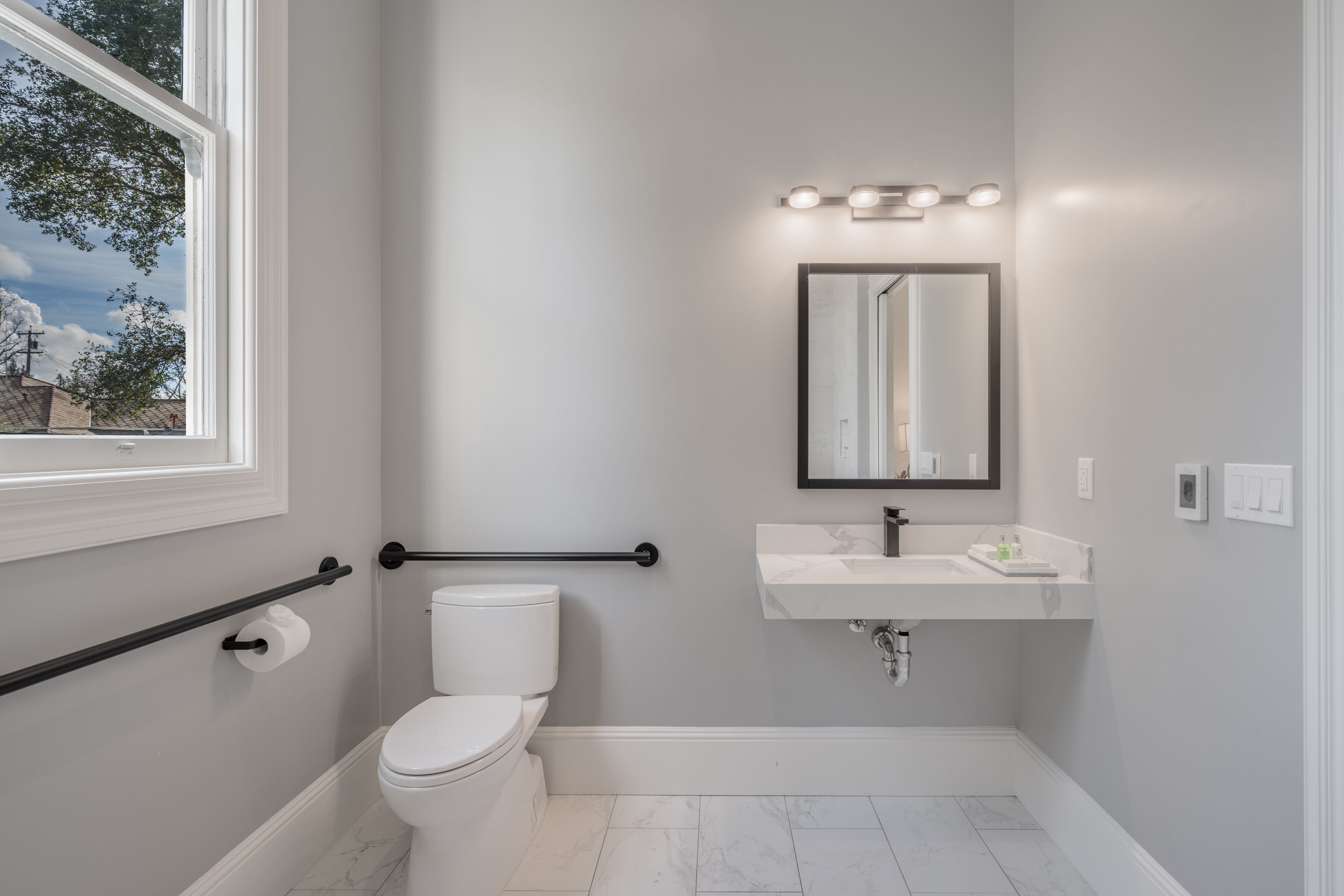 A bathroom with a toilet, sink, and window.
