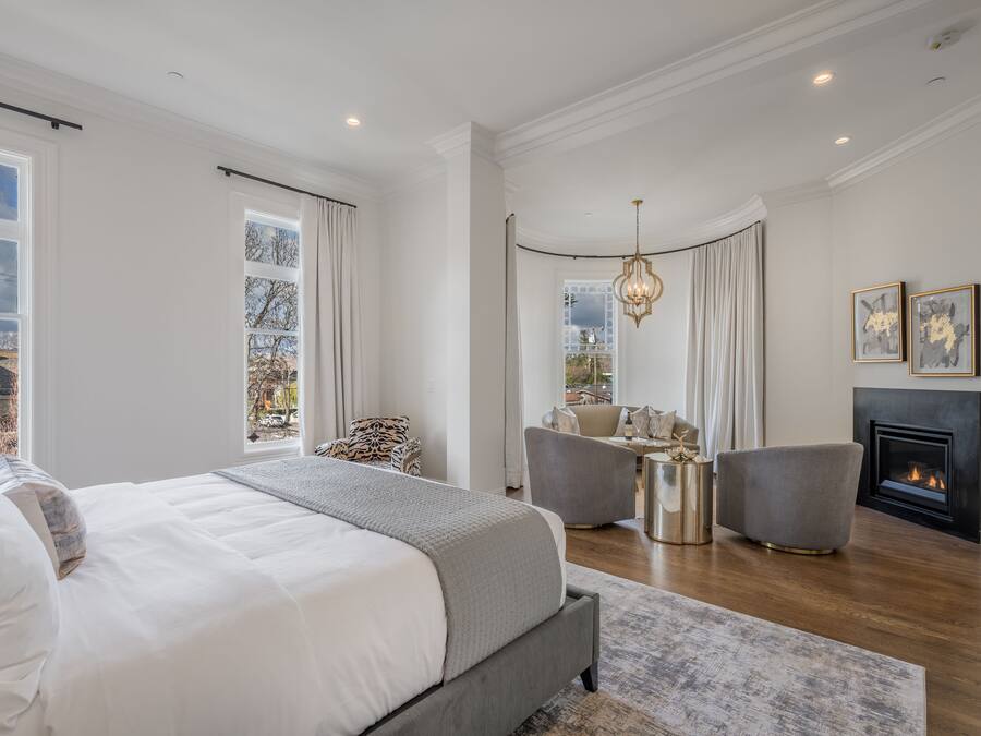 A modern bedroom with a large bed, a fireplace, and a seating area.