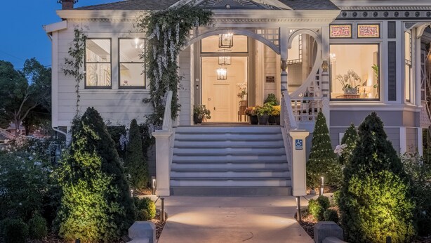 A large, ornate Victorian-style house with a prominent turret, a grand staircase, and a well-lit entrance. - The George Luxury Boutique Inn (Napa)