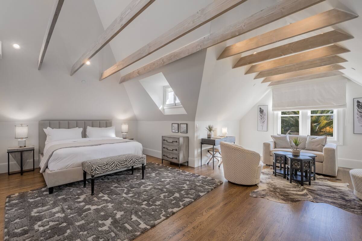 A spacious bedroom with a large bed, a desk, and a sofa.