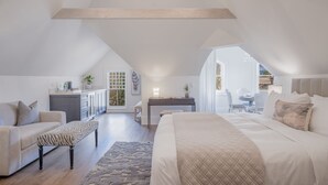 A spacious attic bedroom with a large bed, a sofa, and a desk area. - The George Luxury Boutique Inn (Napa)