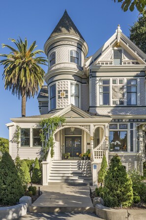 A large, ornate Victorian-style house with a prominent turret, a grand staircase, and a well-maintained front yard with various plants. - The George Luxury Boutique Inn (Napa)