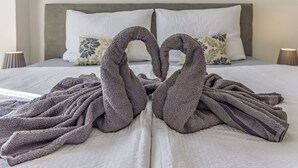 A neatly made bed with two towels arranged in a heart shape.