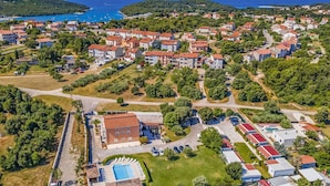 Vue aérienne d’un quartier résidentiel situé sur la côte, avec des maisons, une piscine et une route.