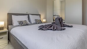 A modern hotel room with a large bed, a nightstand, a bedside lamp, and a large mirror.