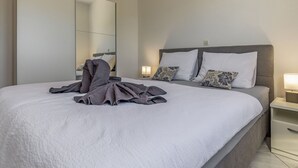 A modern hotel room with a large bed, a bedside table, and a nightstand.