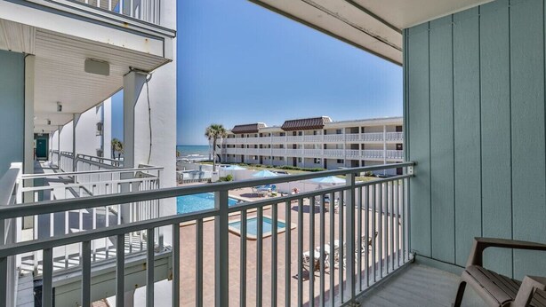 A balcony with a view of a pool and a building across the water. - Ocean View Studio#204-Newly Renovated! (New Smyrna Beach)