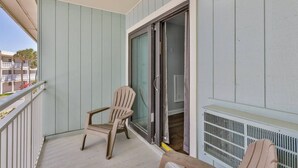 A balcony with a chair, a sliding glass door, and a white radiator. - Ocean View Studio#204-Newly Renovated! (New Smyrna Beach)
