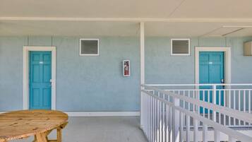 Um quarto com duas portas azul-turquesa, uma janela pequena e um corrimão branco.