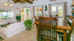 A spacious dining area with a wooden table and chairs, a potted plant, and a view of the outdoors through large windows. - Wonderful private villa for 6 guests with WIFI, hot tub, A/C, TV, patio and pets allowed (Monte Argentario)