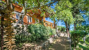 A stone pathway leading to a building with an orange facade and wooden pergola. - Wonderful private villa for 6 guests with WIFI, hot tub, A/C, TV, patio and pets allowed (Monte Argentario)