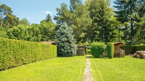 A well-maintained garden with a stone pathway, neatly trimmed hedges, and a wooden structure.
