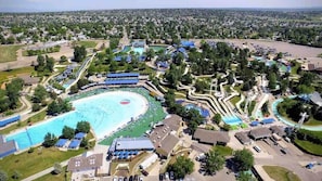 An aerial view of a resort with a large swimming pool, multiple water slides, and a parking area. - $0Fees; Near Park, Dining; Easy Access to Downtown (Northglenn)