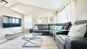 A modern living room with a sectional sofa, a flat-screen TV, and a glass coffee table. - $0Fees; Near Park, Dining; Easy Access to Downtown (Northglenn)