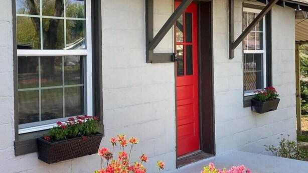 A house with a red door, white exterior walls, and black trim. There are flower boxes on the windowsills. - Tiny Home — Stylish Mt. Holly Retreat — 12 min to CLT & Whitewater Center (Mount Holly)