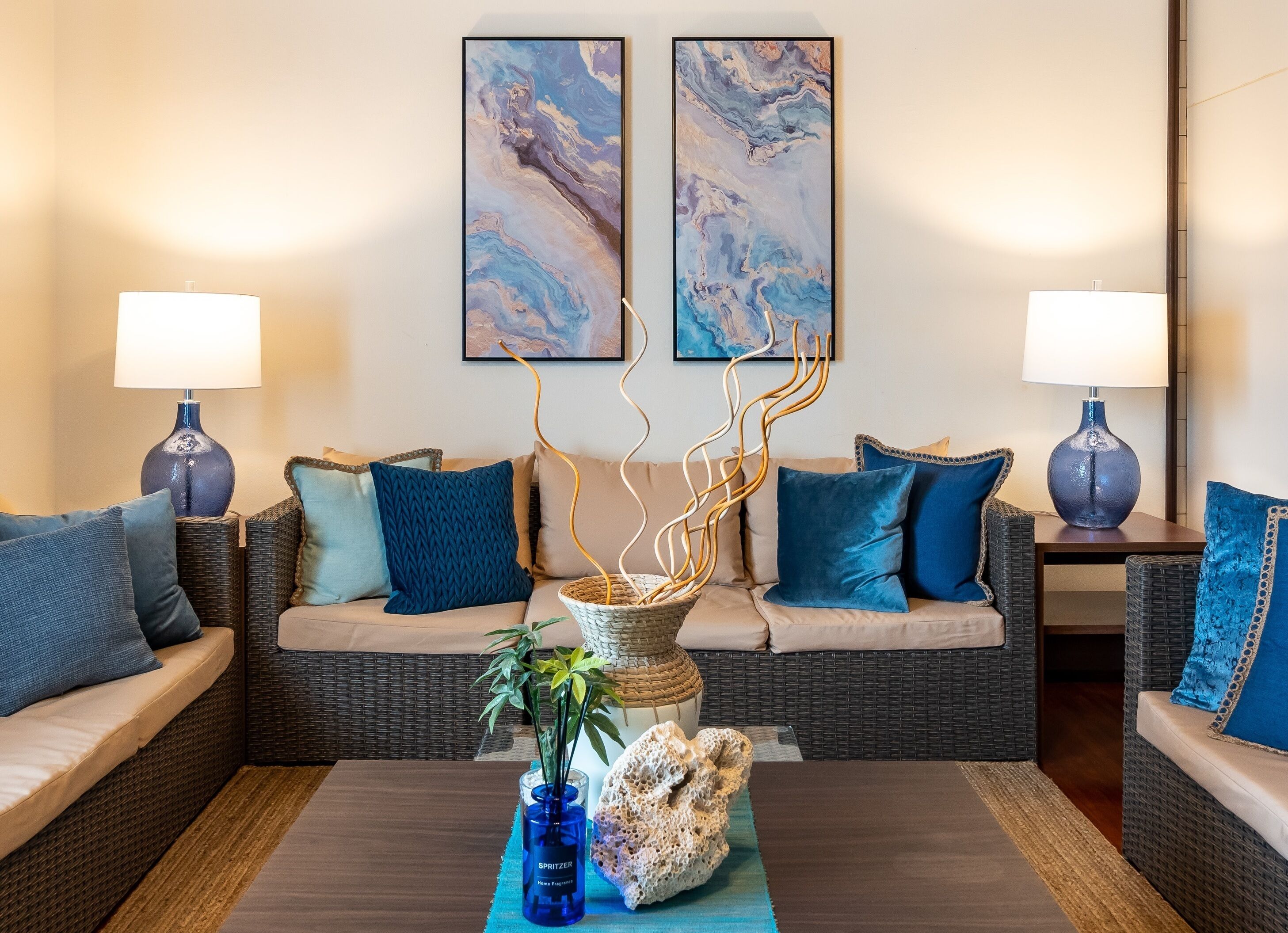 A living room with two sofas, a coffee table, a vase with plants, and two wall-mounted lamps.
