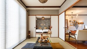 Une chambre de style japonais traditionnel, avec un sol recouvert de tatamis, un lit bas en bois et une table en tatami agrémentée d’un service à thé.