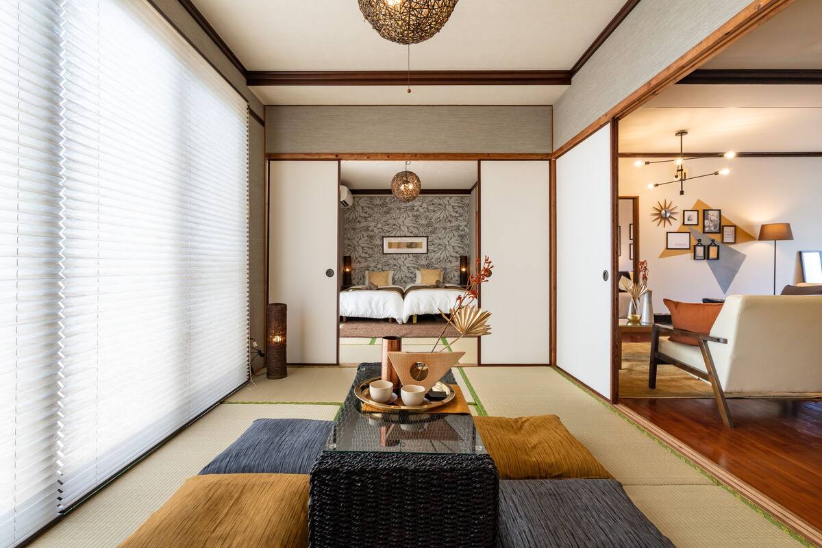Um quarto japonês tradicional com piso de tatame, cama de madeira baixa e uma mesa de tatame com um conjunto de chá.