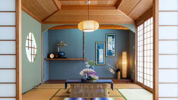 Une pièce de style japonais traditionnel, avec un sol recouvert de tatamis, une petite table en bois et une lampe suspendue.