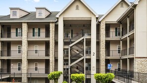A multi-story apartment building with a central staircase, balconies, and a fire escape. - Walk-In 2BR Royal Links Vacation Rental • Sleeps 6 (Branson)