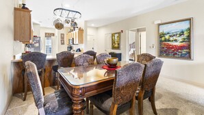 A dining area with a glass-top table, patterned chairs, and a chandelier. - Walk-In 2BR Royal Links Vacation Rental • Sleeps 6 (Branson)