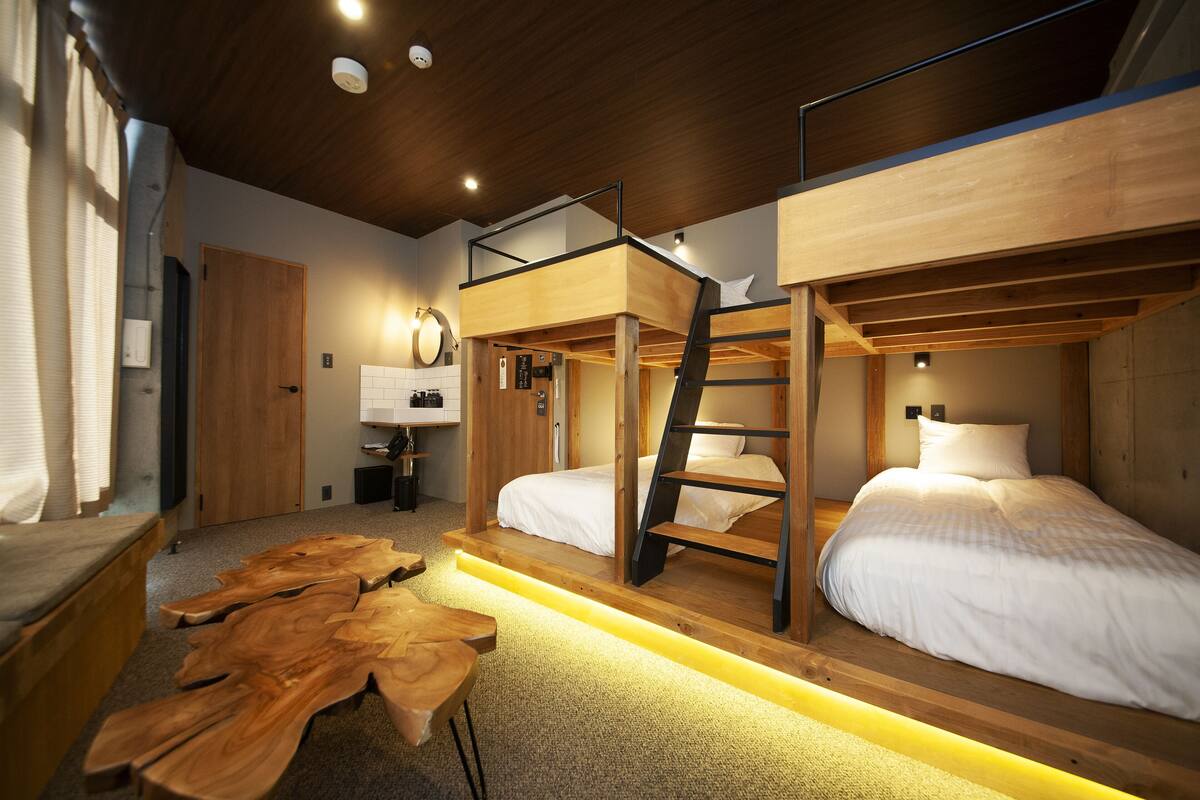 A room with bunk beds, a wooden table, and a desk with a lamp.