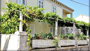 A building with a stone facade, white shutters, and a vine-covered pergola. - Immaculate 4-Bed House in Lumbarda (Lumbarda)