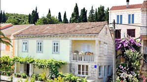 A traditional building with a tiled roof, a balcony with flowers, and a stone facade. - Immaculate 4-Bed House in Lumbarda (Lumbarda)