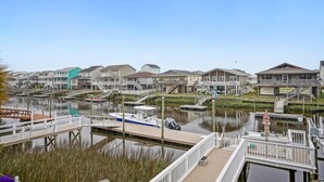 A marina with docked boats, a wooden pier, and a row of houses with a water canal in the foreground. - 4 Bedroom Canal Home! Great Location! (Ocean Isle Beach)