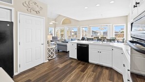 A modern kitchen with white cabinets, a black dishwasher, and a large island with a sink. - 4 Bedroom Canal Home! Great Location! (Ocean Isle Beach)
