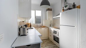 A modern kitchen with white cabinets, a built-in oven, and a large refrigerator.