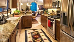 A modern kitchen with granite countertops, stainless steel appliances, wooden cabinets, and a central island. - Lake views, perfect proximity between town and the ski hill ! Immaculately furnished (Whitefish)