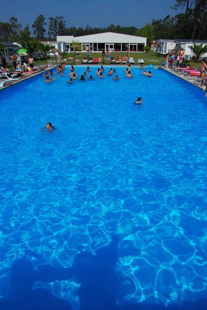 A large outdoor swimming pool surrounded by a building with a covered patio area.