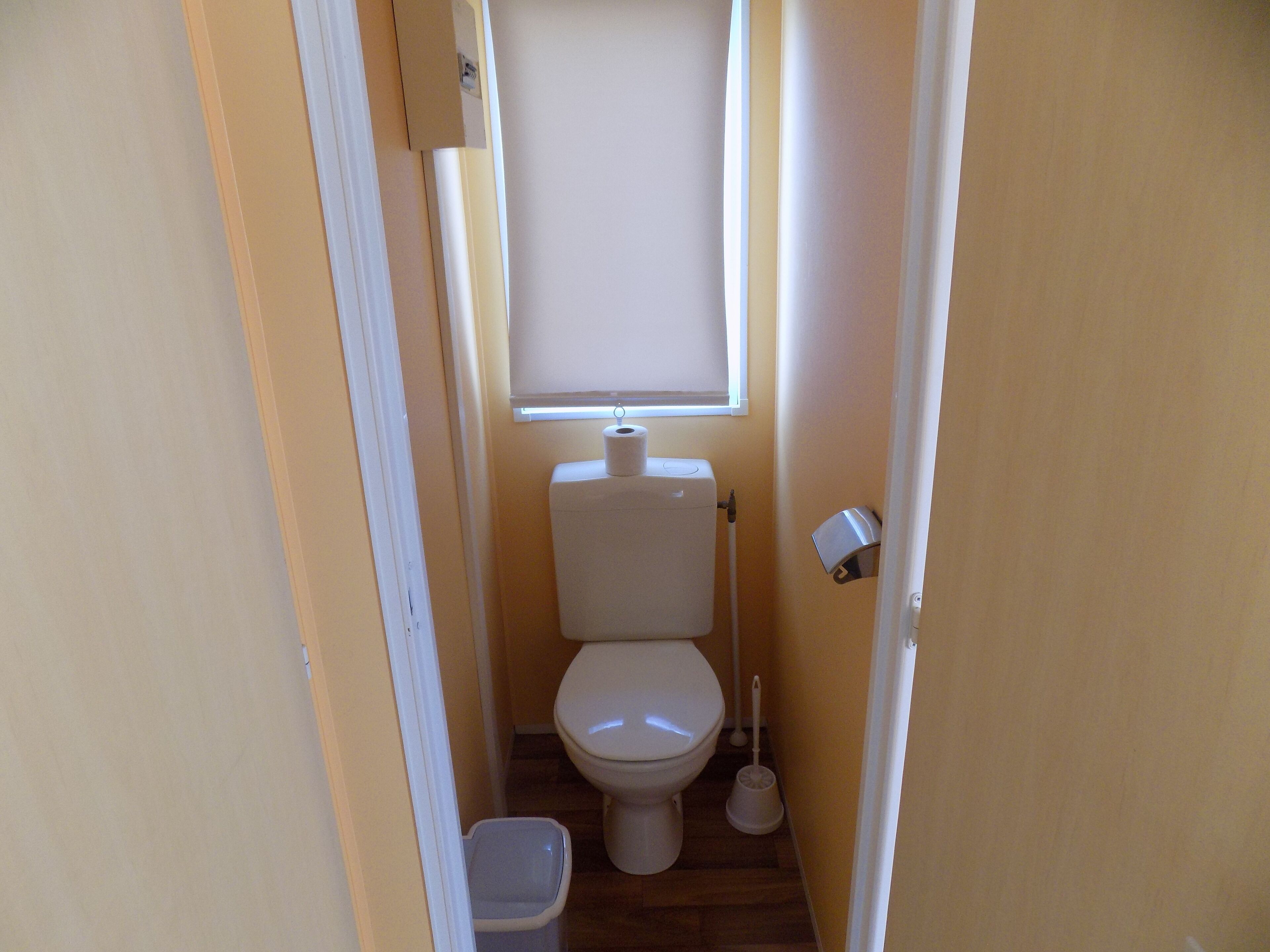 Une petite salle de bain avec des toilettes, un bidet et une fenêtre.
