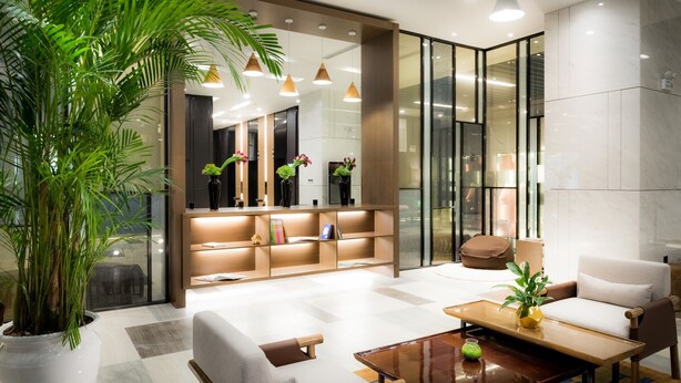 A modern lobby with a sofa, coffee table, and potted plants. - Hotel Jialong By Jingling (Hefei)